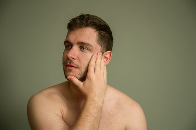 man touches acne free skin